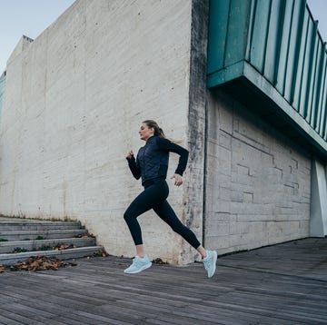 woman running touch-strap against modern building