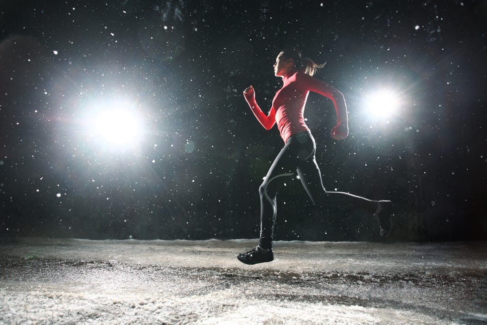 mujer corriendo en la noche mientras nieva