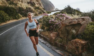 woman running on the road around mountains