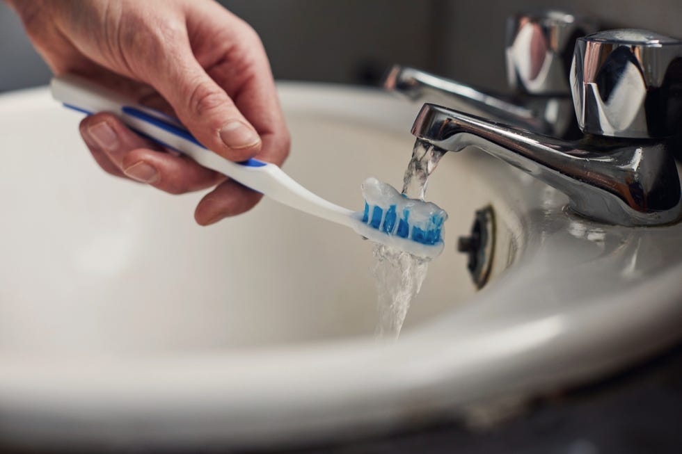 woman running toothbrush under a tap