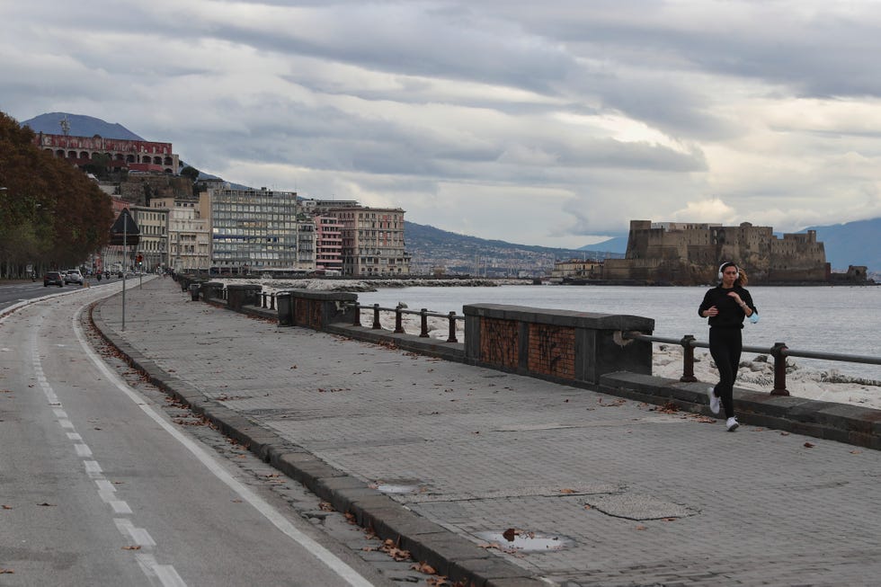 a woman runs along an empty promenade in naples the