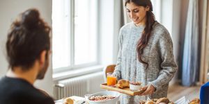 Woman serving breakfast to boyfriend at table