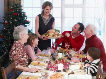 una mujer sirve un pavo a su familia en la comida de navidad