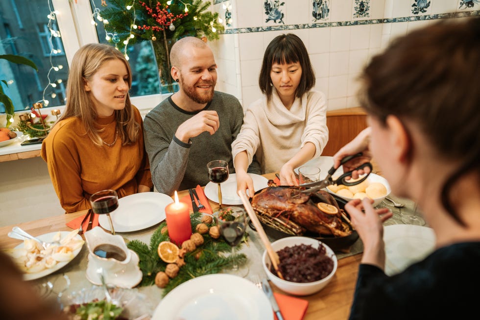 woman serving his family stuffed turkey on thanksgiving dinner at dining table