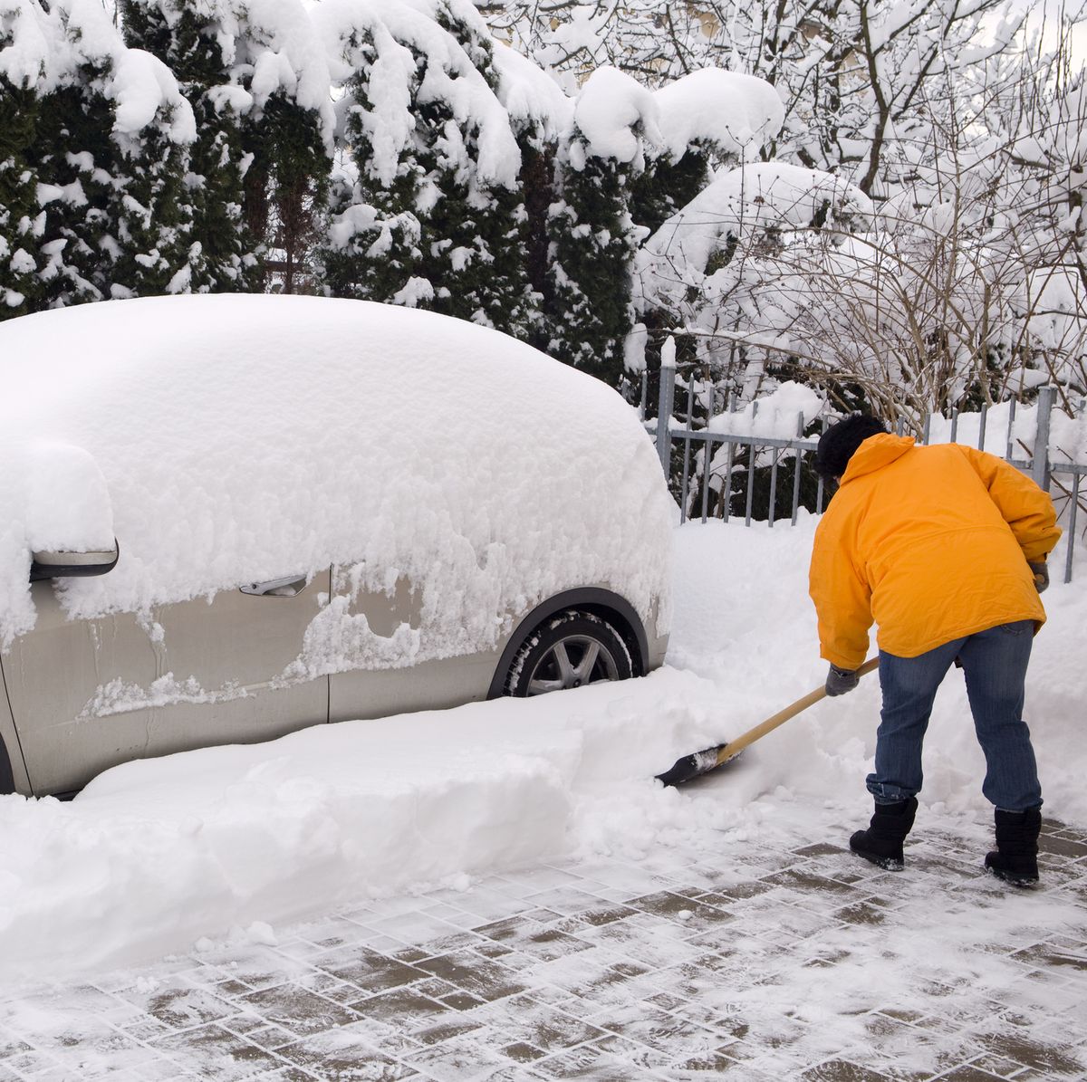 Woman shovelling around snow covered car