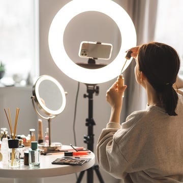 woman showing lipgloss while recording a video tutorial at home