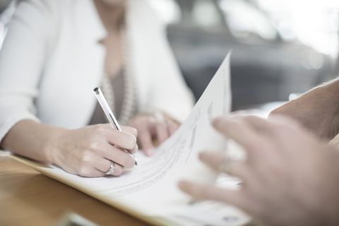 Woman signing contract at desk at car dealership