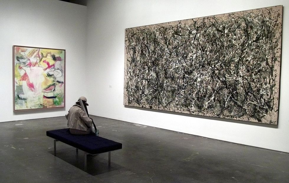 a woman sits on a bench between the paintings "one