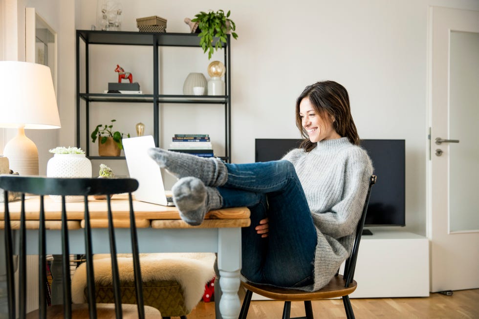 virtual birthday party - Woman sitting at table with feet up, using laptop