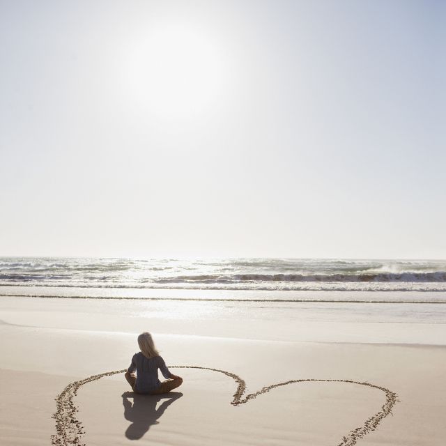 woman sitting cross legged in heart on beach