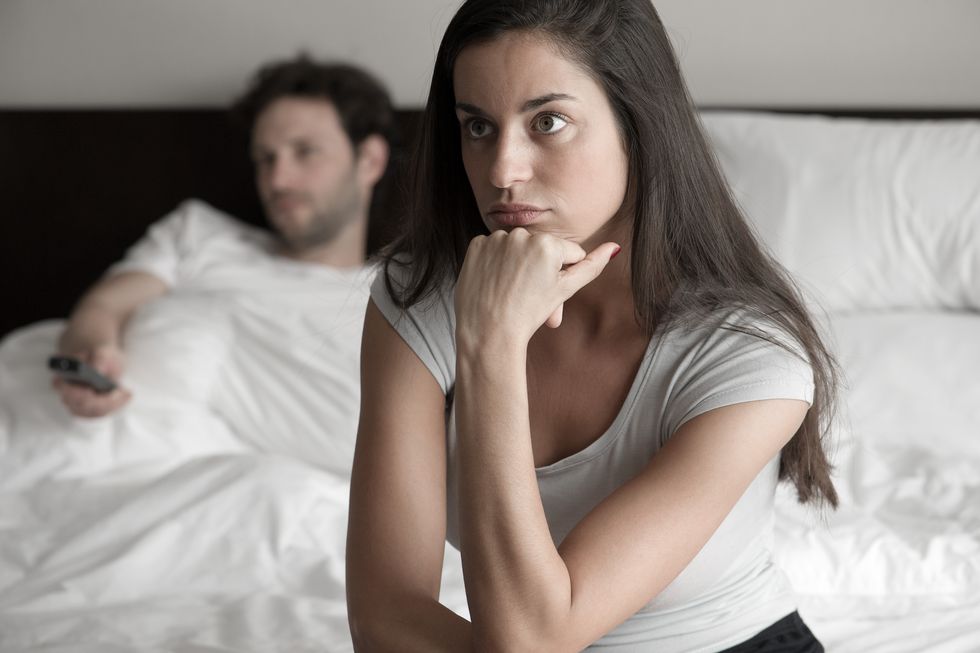 woman sitting in bed while husband watching tv