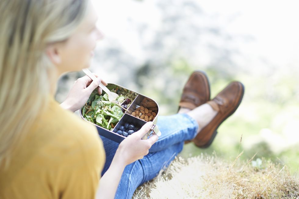 woman sitting in countryside eating healthy plastic free lunch