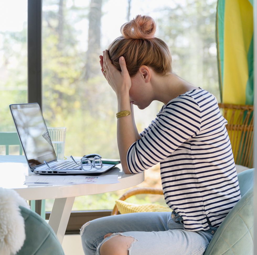 woman sitting in front of laptop with head in hands