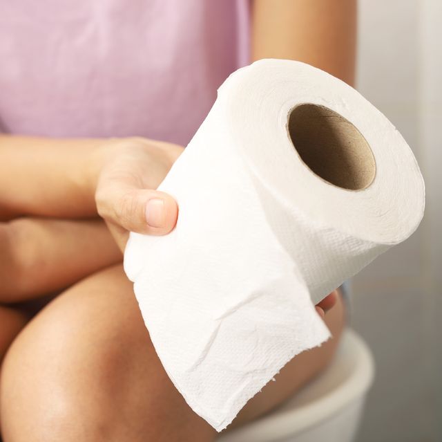 woman sitting in the bathroom holding toilet paper