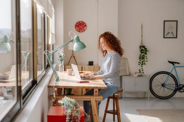 woman sitting on a desk using a laptop computer while working from home