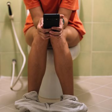 woman sitting on a toilet holding a mobile phone in her hands