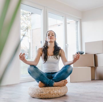 woman sitting on cushion in her new apartment, meditating
