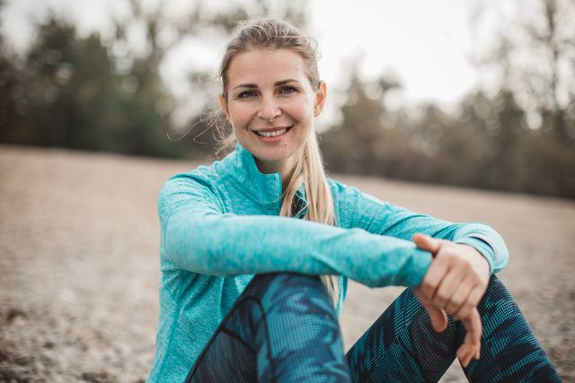 mujer rubia sentada frente a lago