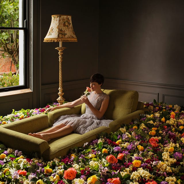 woman sitting on sofa surrounded by flowers