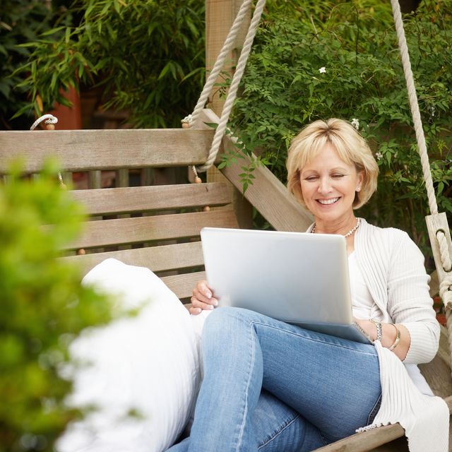Woman sitting on swing using laptop