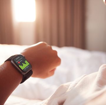 woman sitting up in bed looking at screen of smart watch