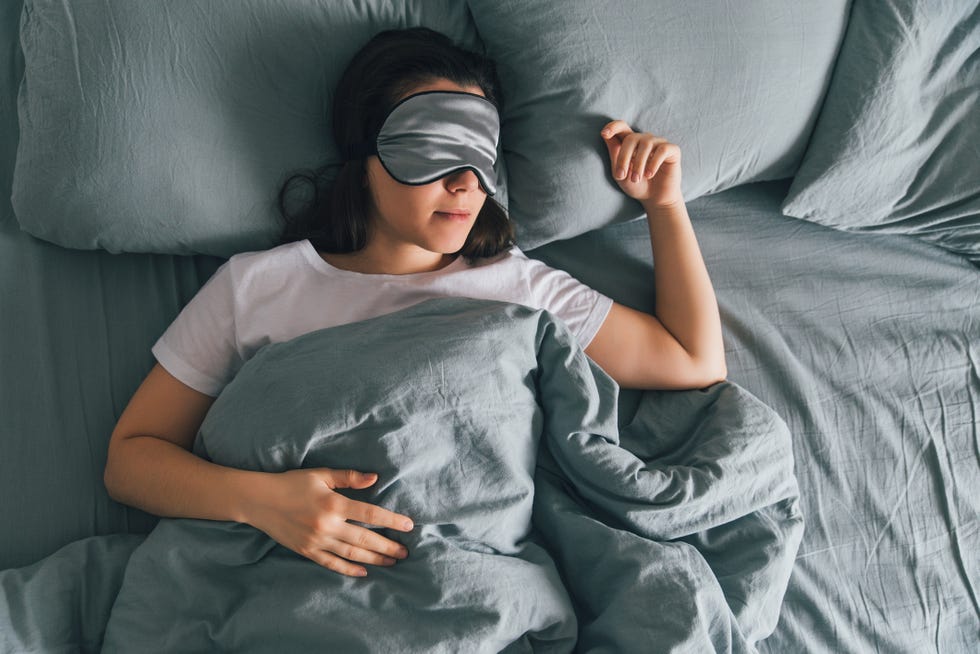 woman sleep in eye patch in grey bed copy space