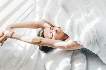 woman sleeping under duvet at the sunny morning, top view