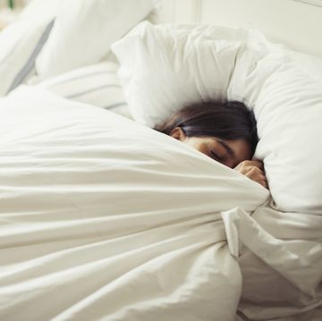 woman sleeping in bed under covers
