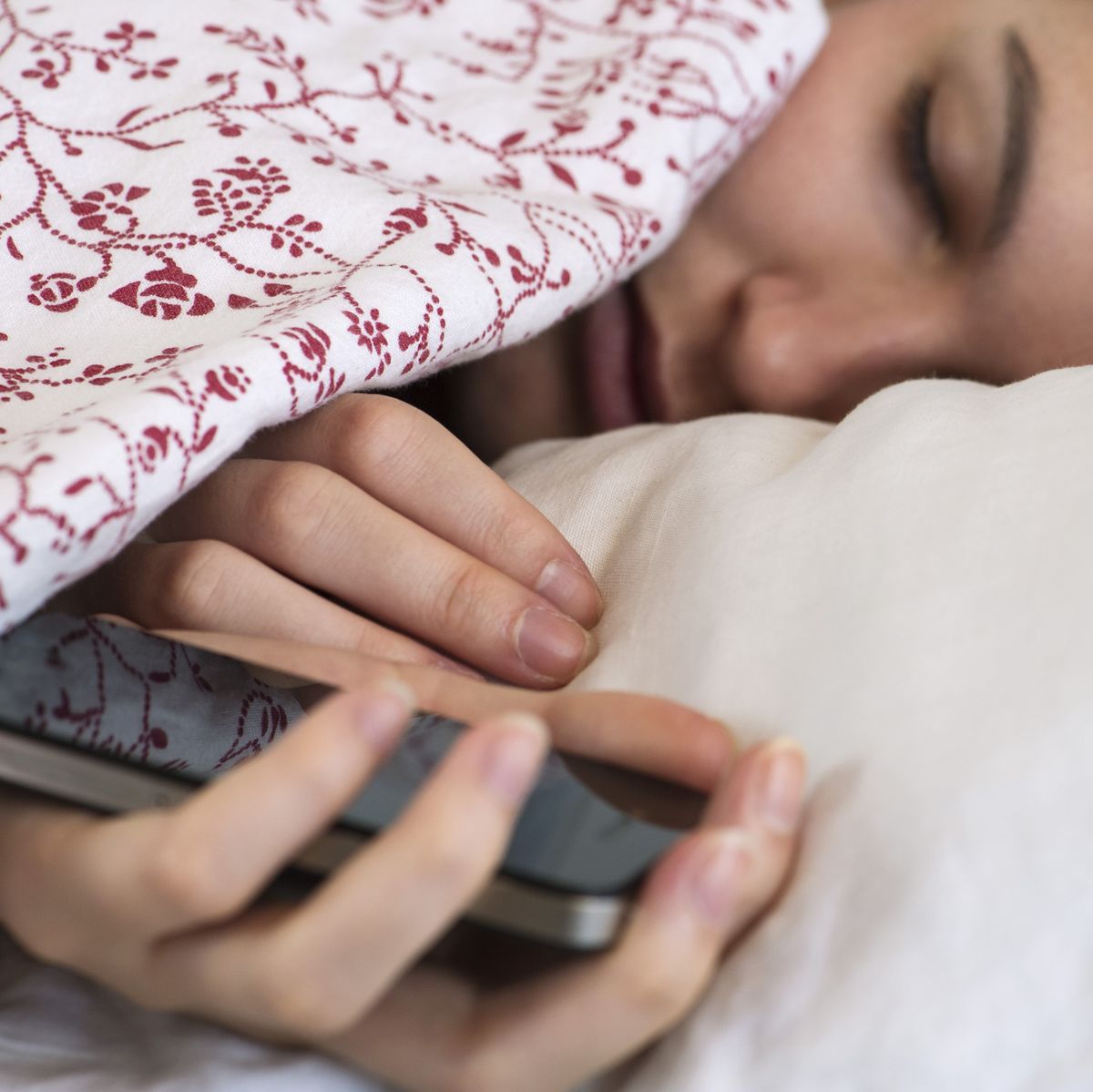 Woman sleeping in bed with smartphone in hand
