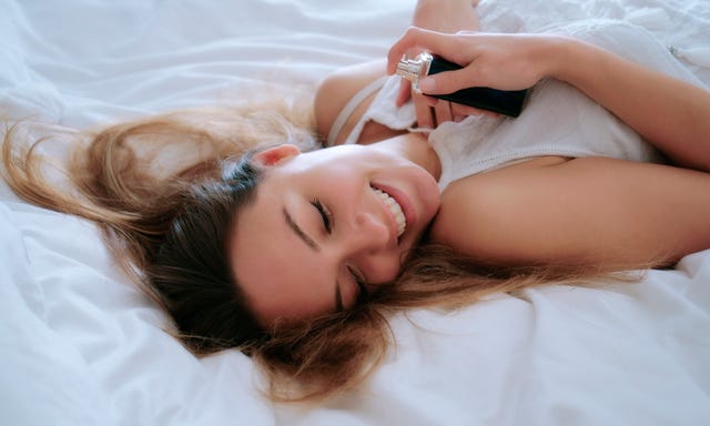 woman smiling holding perfume bottle