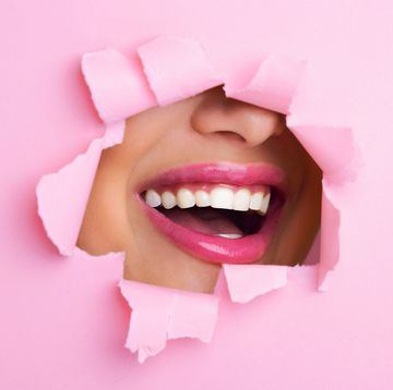 woman smiling through hole in pink paper