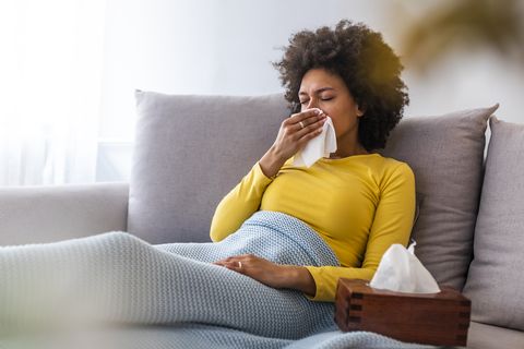 woman sneezing in a tissue in the living room