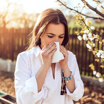 woman sneezing in the blossoming garden