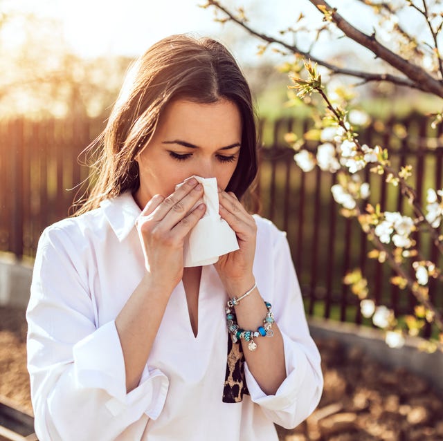 woman sneezing in the blossoming garden