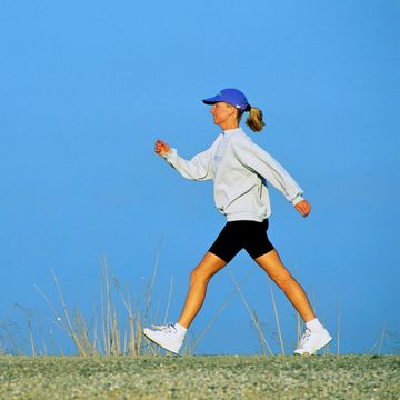 woman speed walking, profile, against blue sky