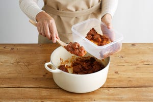 woman spooning meat into tupperware