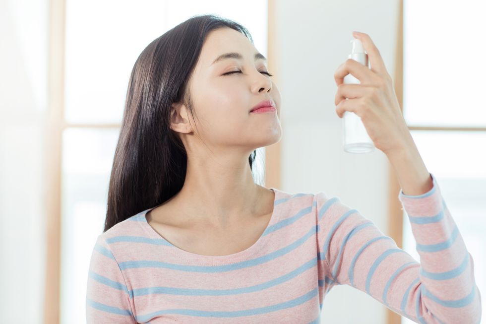 a woman spraying mist on her face
