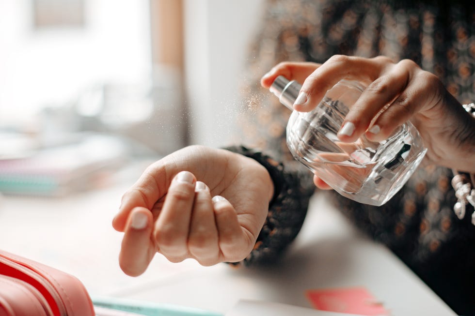 woman spraying perfume on wrist