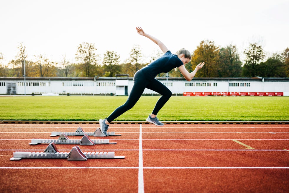 woman sprinting off start line on outdoor running track