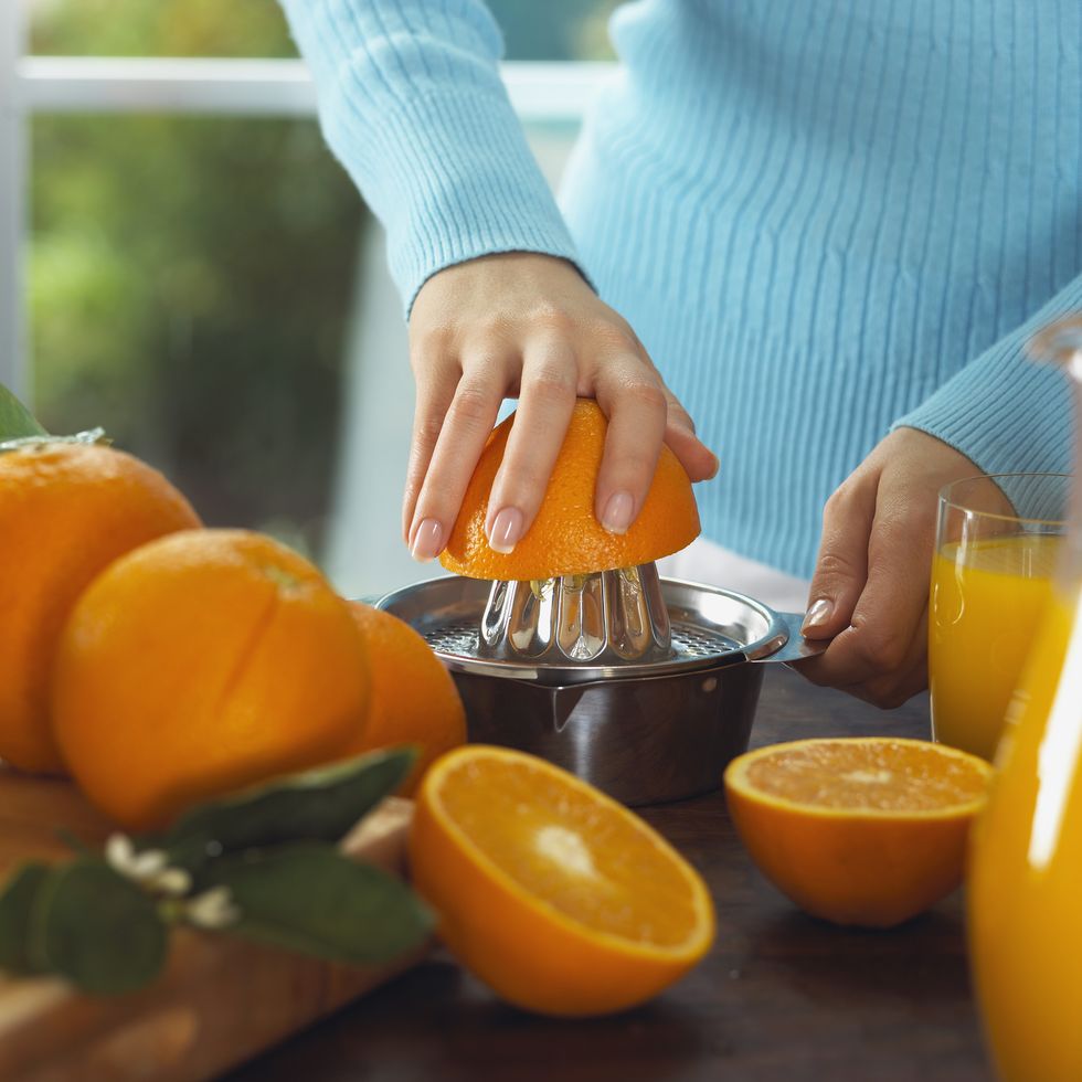 mulher espremendo laranjas em suco de laranja