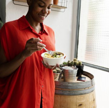 woman standing at home eating bowl of salad