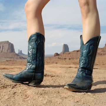 woman standing in desert wearing cowboy boots
