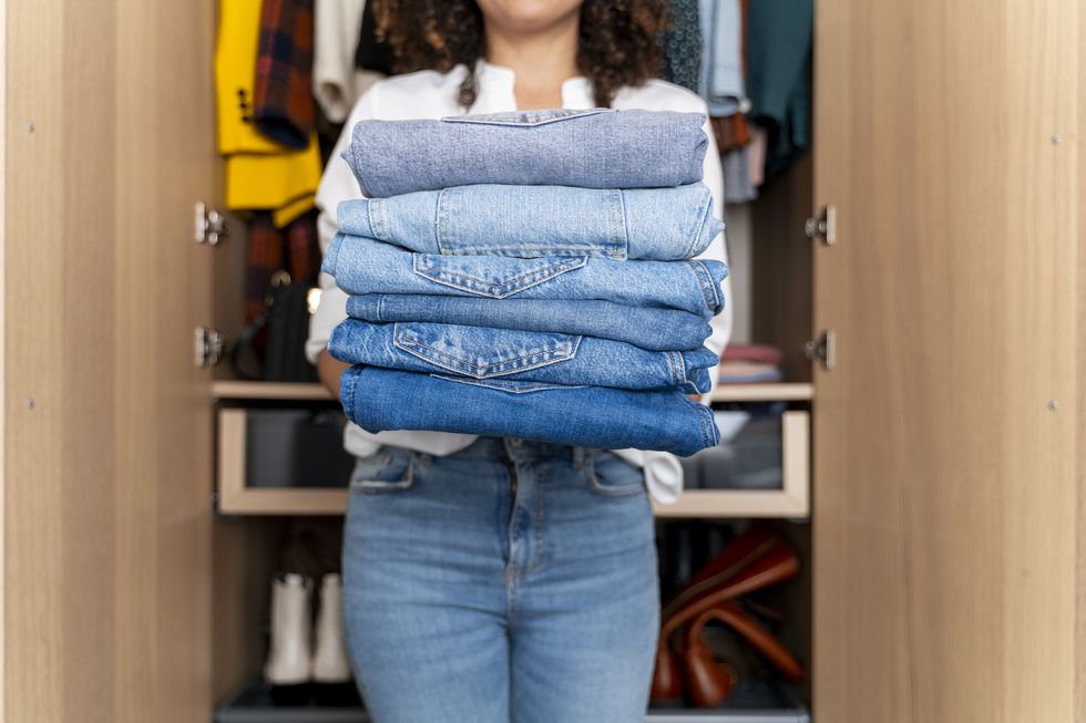 https://hips.hearstapps.com/hmg-prod/images/woman-standing-on-front-of-wardrobe-holding-stack-royalty-free-image-1680125181.jpg?crop=1xw:1xh;center,top&resize=980:*