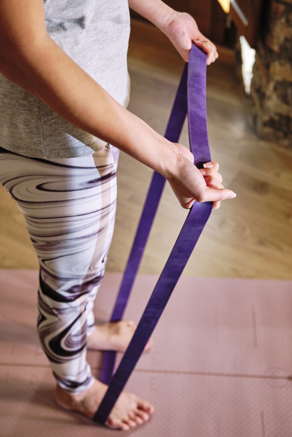 woman standing on resistance band while exercising at home