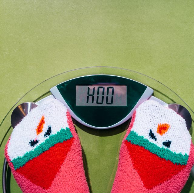 woman standing on the scales in christmas fun red green socks with snowman background the problem of excess weight gained during the holiday new year
