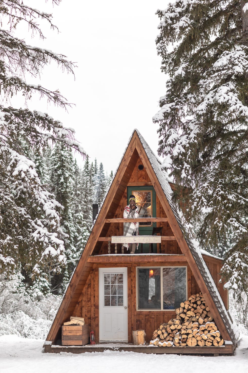 Woman stands alone on balcony of a-frame winter cabin woman stands alone on balcony of a frame winter cabin