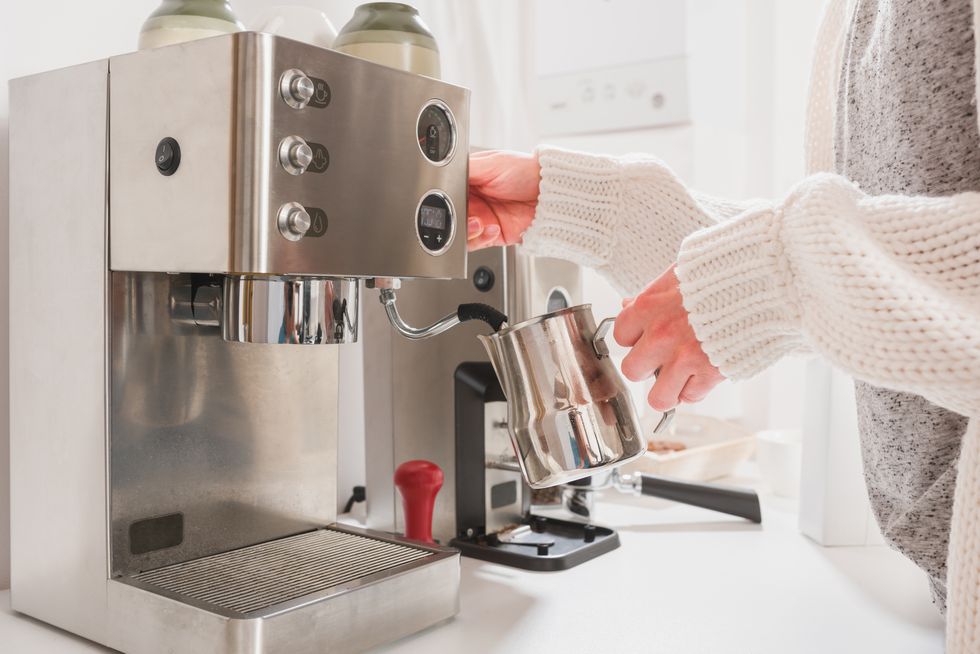 woman steaming milk for cappuccino on professional espresso machine