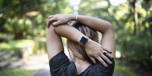 Woman stretching on a trail with a fitness tracker