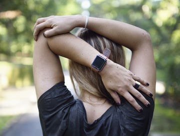 Woman stretching on a trail with a fitness tracker