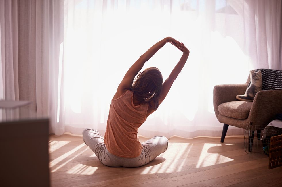 Woman doing light exercise and stretching in bedroom